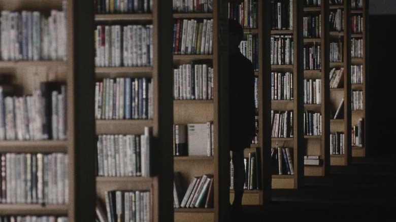 Human silhouette standing between DVD racks in Pulse