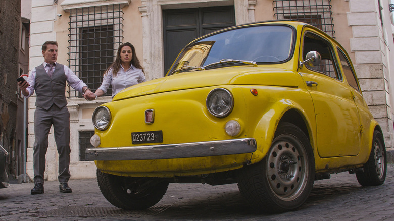 Ethan and Grace stand beside a yellow Fiat