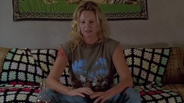 Charlize Theron as Aileen Wuornos smokes with troubled expression in Monster