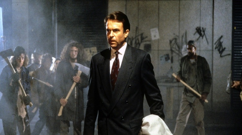 John Trent wearing a suit and surrounded by gang members in In the Mouth of Madness