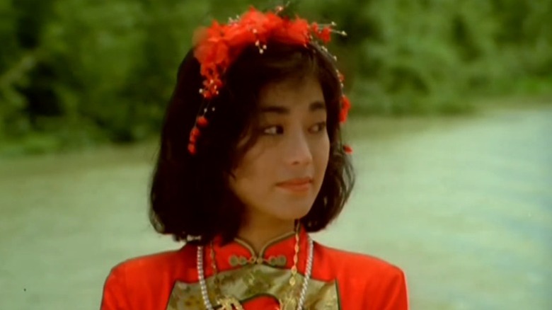 Jenny wearing a traditional red dress and a red flower crown and looking to her side in Eight Taels of Gold