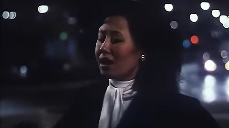 Zhaohong with her eyes closed in front of blurred city eyes at night in Full Moon in New York