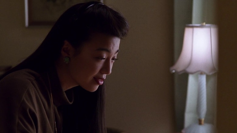 June sitting while looking down and giving a sad smile in The Joy Luck Club