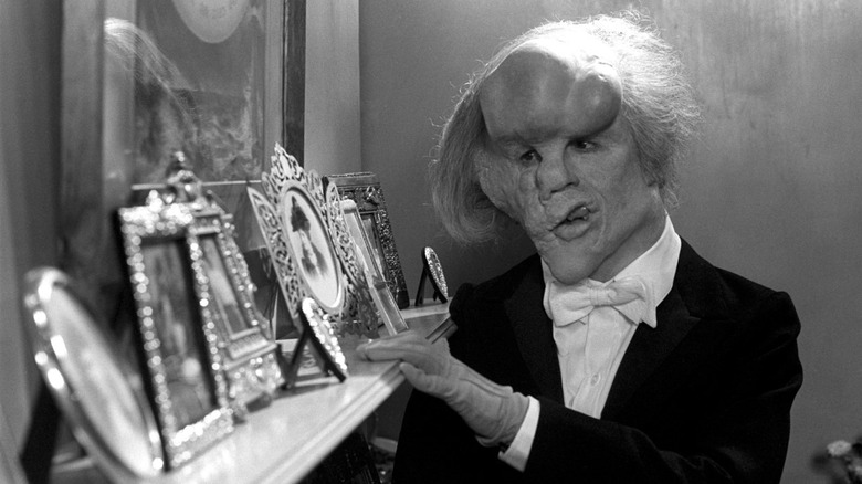 John Merrick looking at framed pictures on a sill in The Elephant Man (1980)