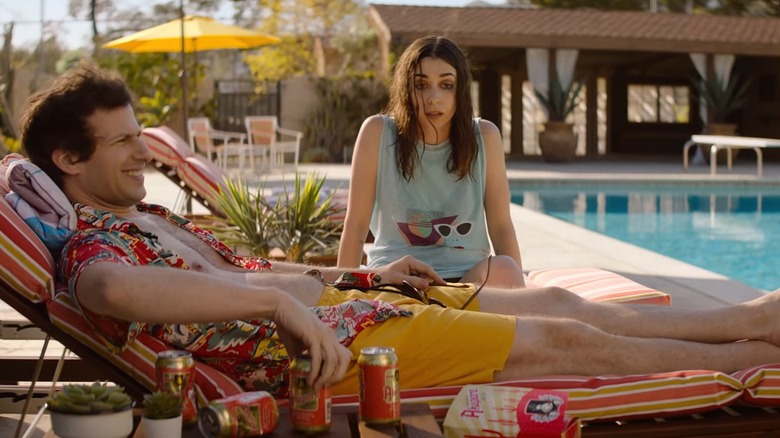 Nyles reclining on a lounge chair and Sarah looking shell-shocked next to a pool in Palm Springs