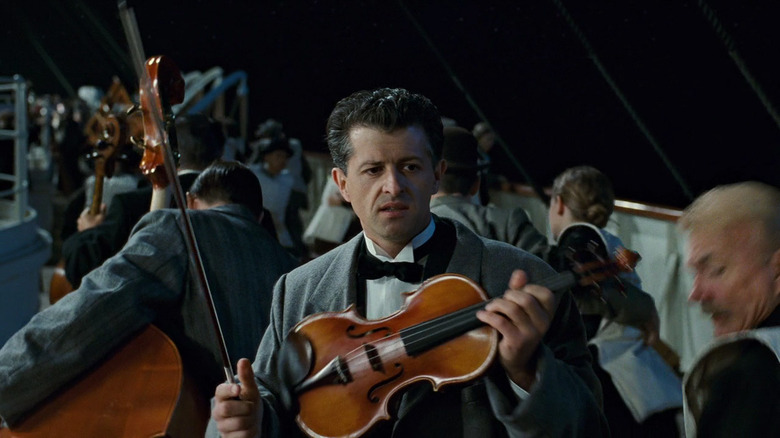 Man holding violin on deck in Titanic