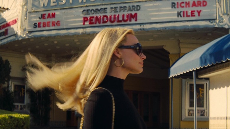 Margot Robbie walking in front of movie theater