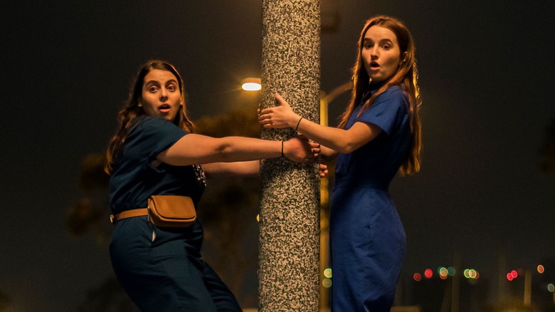 Kaitlyn Dever and Beanie Feldstein in Booksmart hug pole