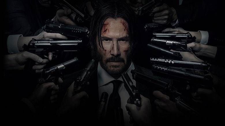 John Wick with a myriad of guns aimed at him