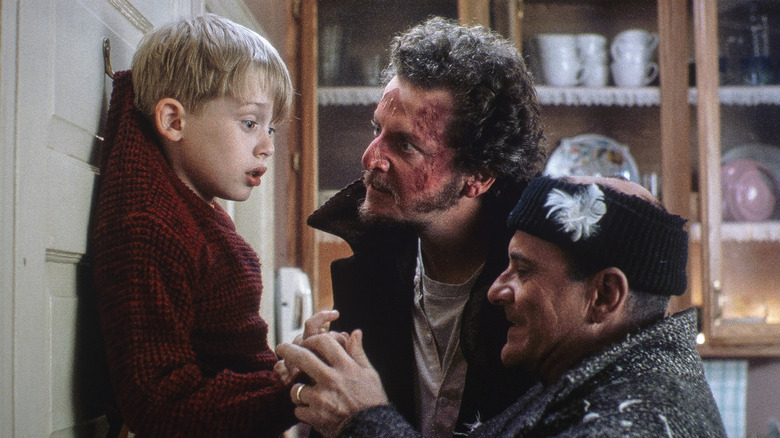 Macaulay Culkin as Kevin hangs on a door while Joe Pesci as Harry and Daniel Stern as Marv attack in Home Alone