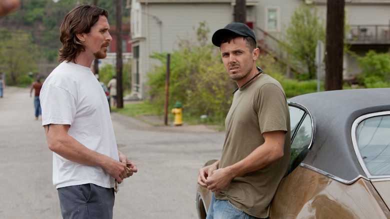 Christian Bale and Casey Affleck lean on car Out of the Furnace