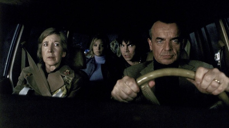 A family of four sits in a darkened car