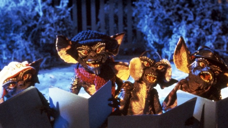 Four gremlins caroling in winter garb