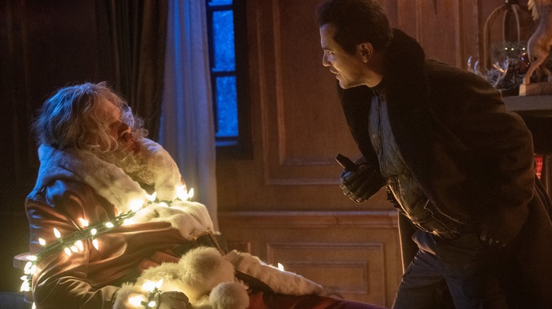Scrooge confronts Santa, who's tied up in Christmas lights