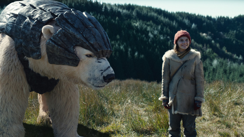 Dafne Keen as Lyra standing in a field with her armored polar bear in His Dark Materials