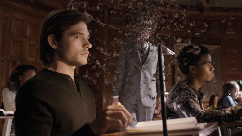 Jason Ralph as Quentin Coldwater, sitting at his desk as bugs fly around him in The Magicians