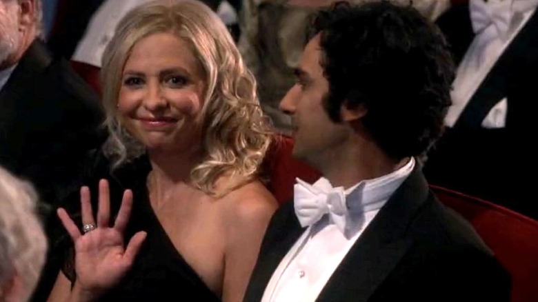 Sarah Michelle Gellar as herself waves and wears a black evening gown while sitting next to Kunal Nayyar as Raj Koothrappali who is wearing a tux and looking at her on The Big Bang Theory