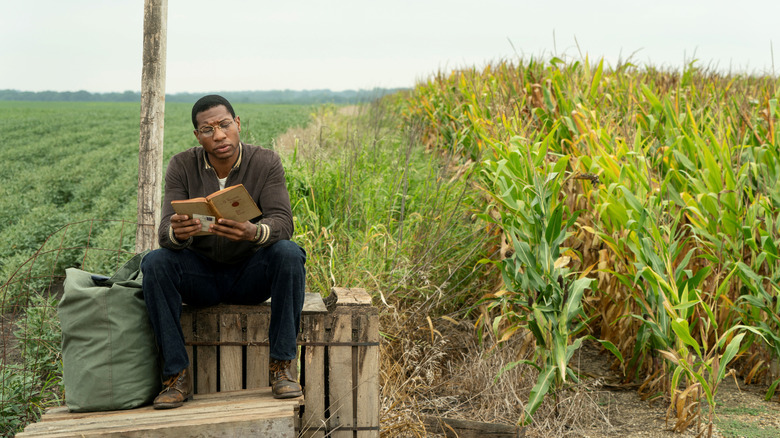 Lovecraft Country's Jonathan Majors sitting on crate reading