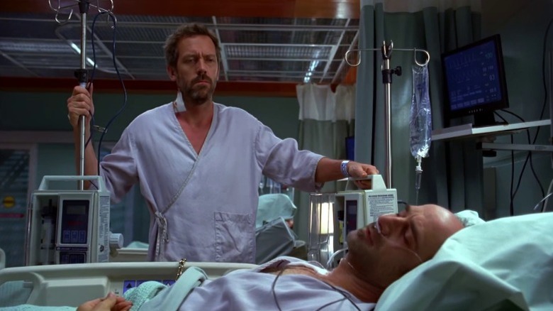 Hugh Laurie as Dr. Gregory House looks at Elias Koteas as Jack Moriarty in a hospital bed onHouse