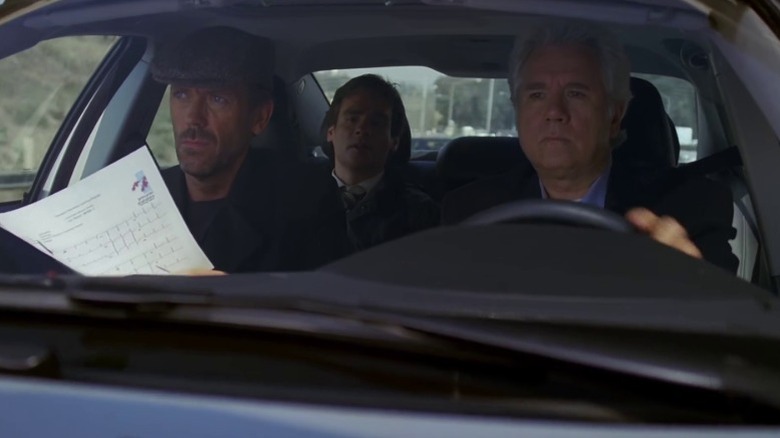 Hugh Laurie as Dr. Gregory House, Robert Sean Leonard as Dr. James Wilson, and John Larroquette as Gabriel Wozniak driving in a car on House