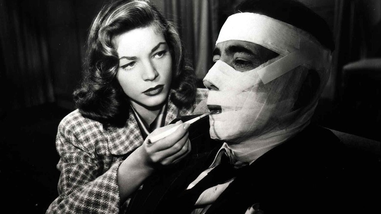 Lauren Bacall gives bandaged Humphrey Bogart a cigarette