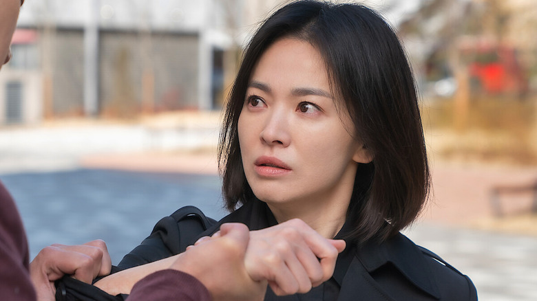 Dong-eun (Song Hye-kyo) glares as her wrist is grabbed in The Glory