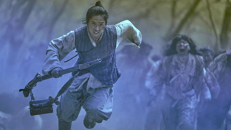 Yeong-shin (Kim Sung-kyu) flees from zombies while holding a musket in Kingdom