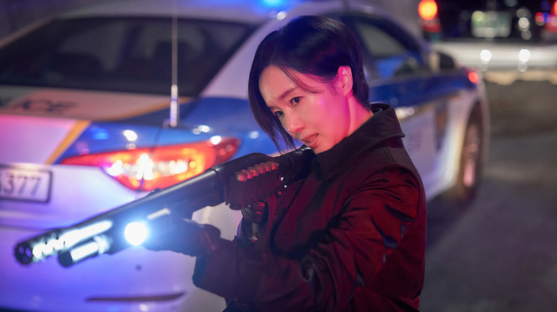 Choi Jun-kyun (Lee Jung-hyun) aims a shotgun by a police car in Parasyte: The Grey