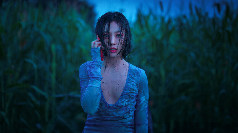 A disheveled Yoo Seong-a (Go Min-si) is on her phone among reeds in The Frog