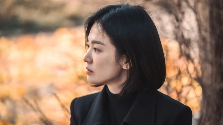 Moon Dong-eun (Song Hye-kyo) stands by an autumnal tree in The Glory