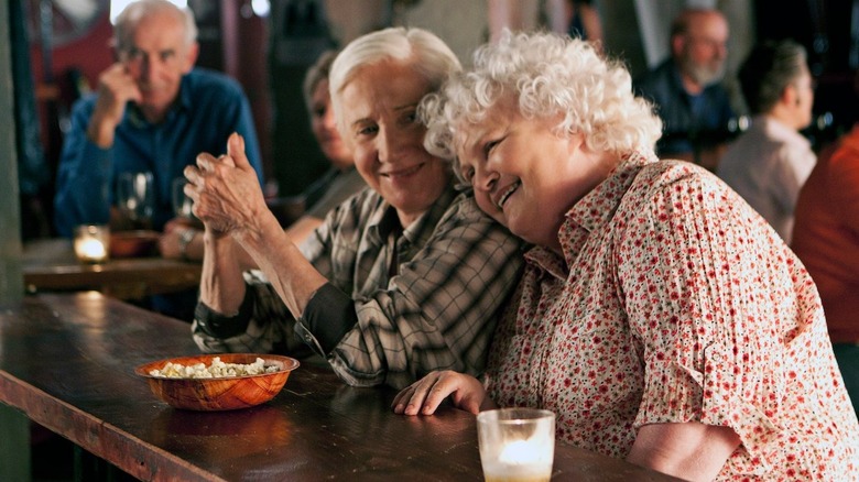 Two older women lean on each other