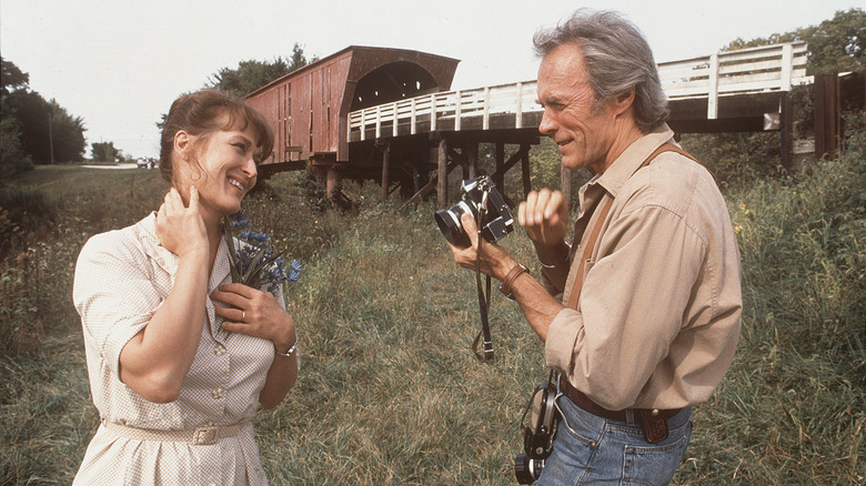 Clint Eastwood as Robert taking a picture of Meryl Streep as Francesca holding flowers in The Bridges of Madison County