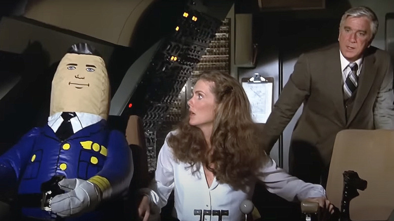 Julie Hagerty as Elaine Dickinson and Leslie Nielsen as Dr. Rumack glance at an inflatable autopilot in Airplane!