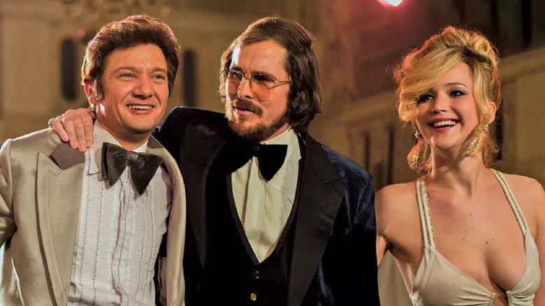 Jeremy Renner as Mayor Carmine Polito hangs out with Christian Bale as Irving Rosenfeld and Jennifer Lawrence as Rosalyn Rosenfeld in American Hustle