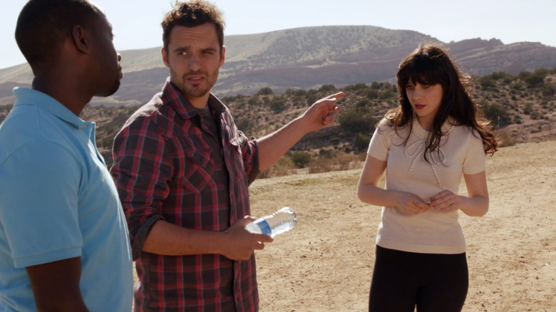 Nick Miller pointing toward Jess while looking at Winston on New Girl