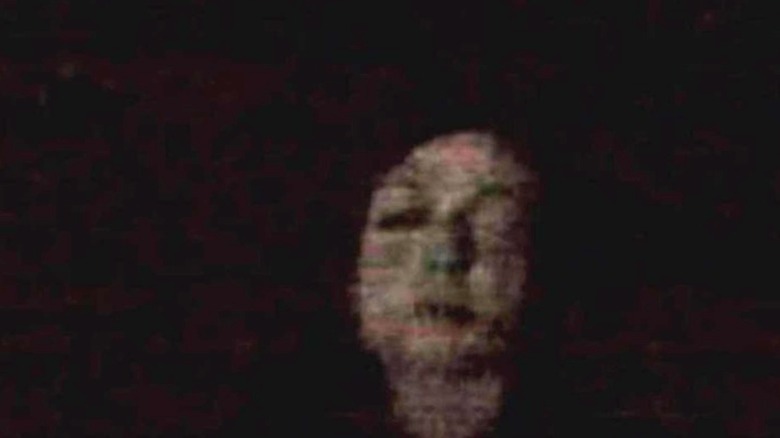 A blurry image of a bloated face floating in the dark.