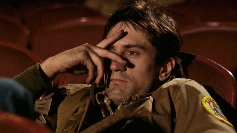 Robert De Niro as Travis Bickle sitting in a movie theater in Taxi Driver