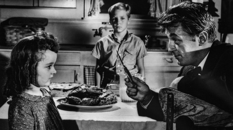 Harry (Robert Mitchum) showing knife to Pearl (Sally Jane Bruce) in The Night of the Hunter