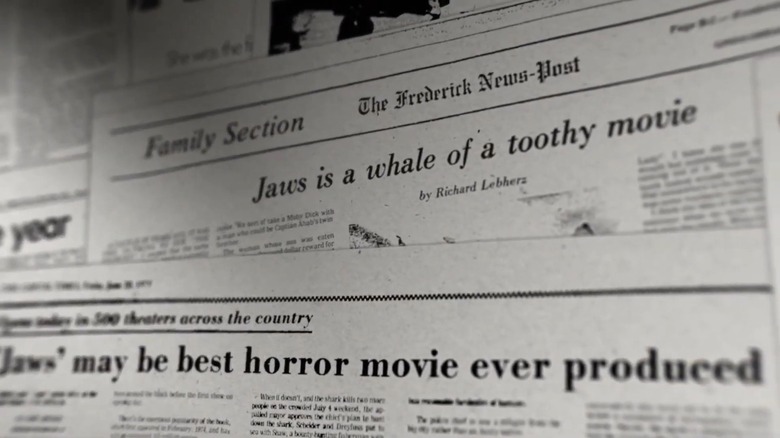 A newspaper collage featuring headlines "Jaws is a whale of a toothy movie" and "Jaws may be best horror movie ever produced"