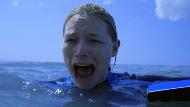 Zoe Naylor as Kate, floating in water with just her head visible, mouth open in a scream