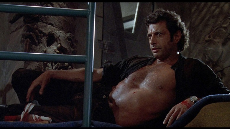 Ian Malcolm shirtless and injured, reclining