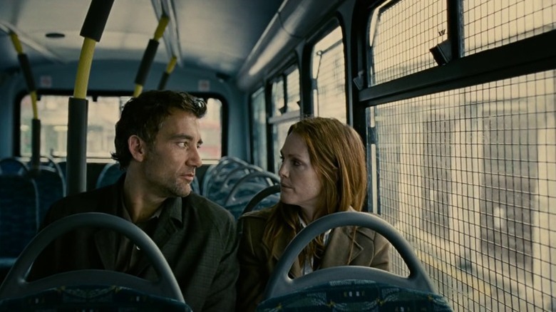 Clive Owen as Theo Faron and Julianne Moore as Julian Taylor sitting on a bus and looking at each other in Children of Men