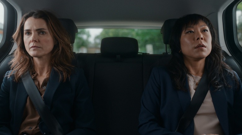 Keri Russell's Kate and Ali Ahn's Eidra sit stoically in the back of a car in The Diplomat