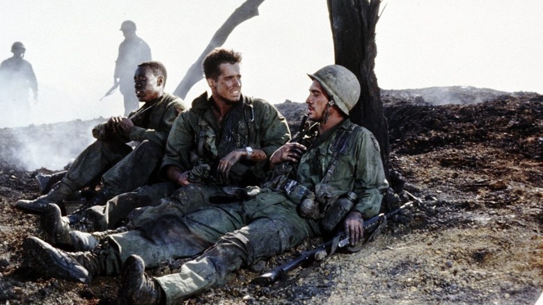 Don Cheadle as Washburn resting under a tree with other soldiers in Hamburger Hill