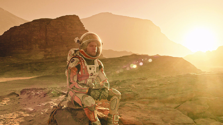 Mark Watney sits on the Martian landscape