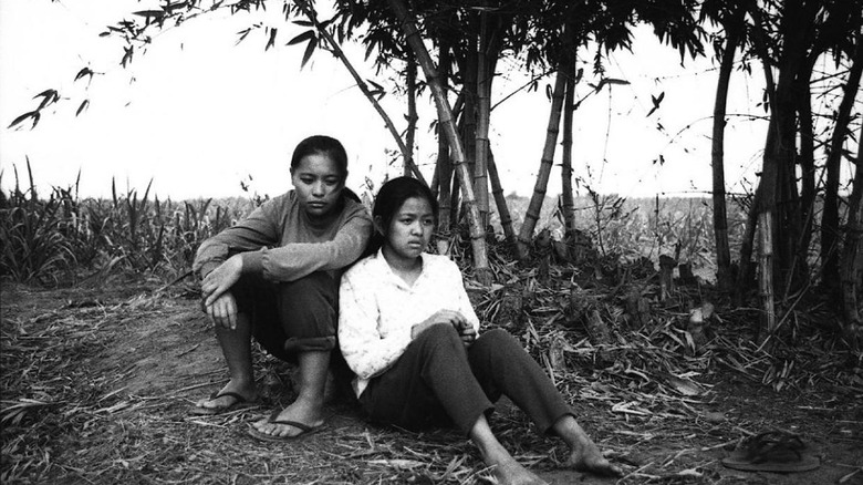 Two sisters sit together under forest trees in "Evolution of a Filipino Family"