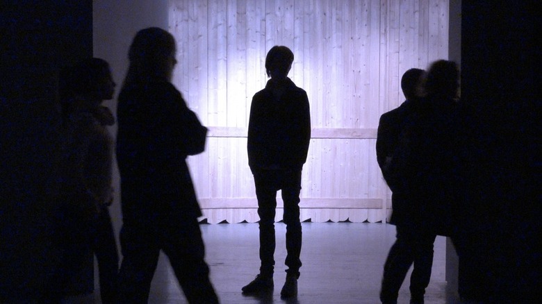 The silhouette of Adam Szymczyk standing still behind a moving crowd in "exergue – on documenta 14"