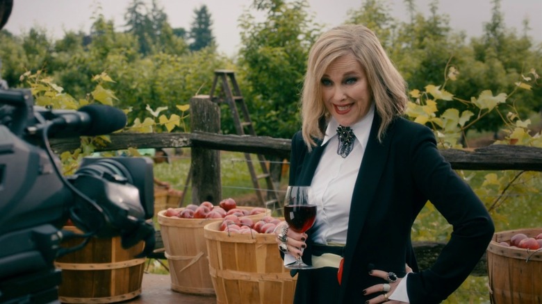 Moira Rose holding a glass of wine