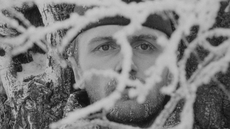 Boris Plotnikov as Sotnikov peering through snow-covered three branches in The Ascent