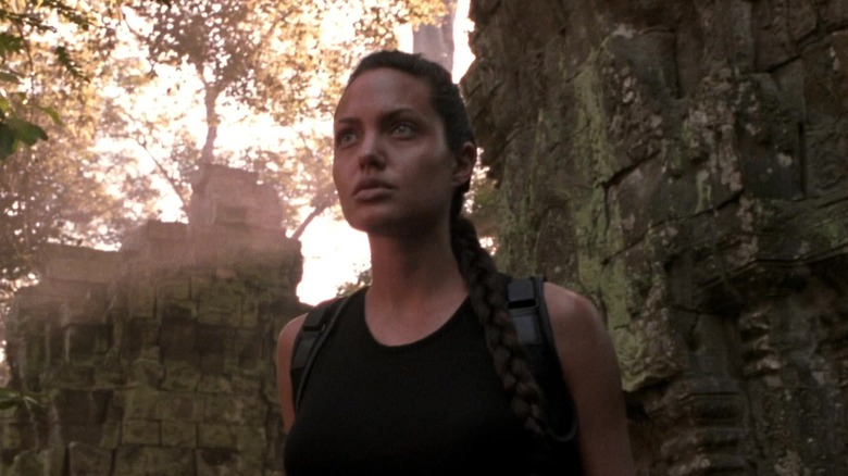 Angelina Jolie as Lara Croft, standing in wooded ruins in Lara Croft: Tomb Raider